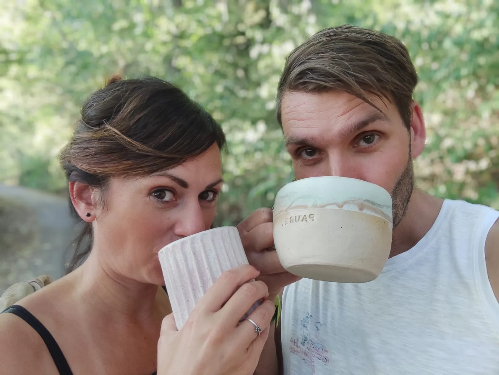 Zwei Personen trinken aus handgetöpferten Tassen