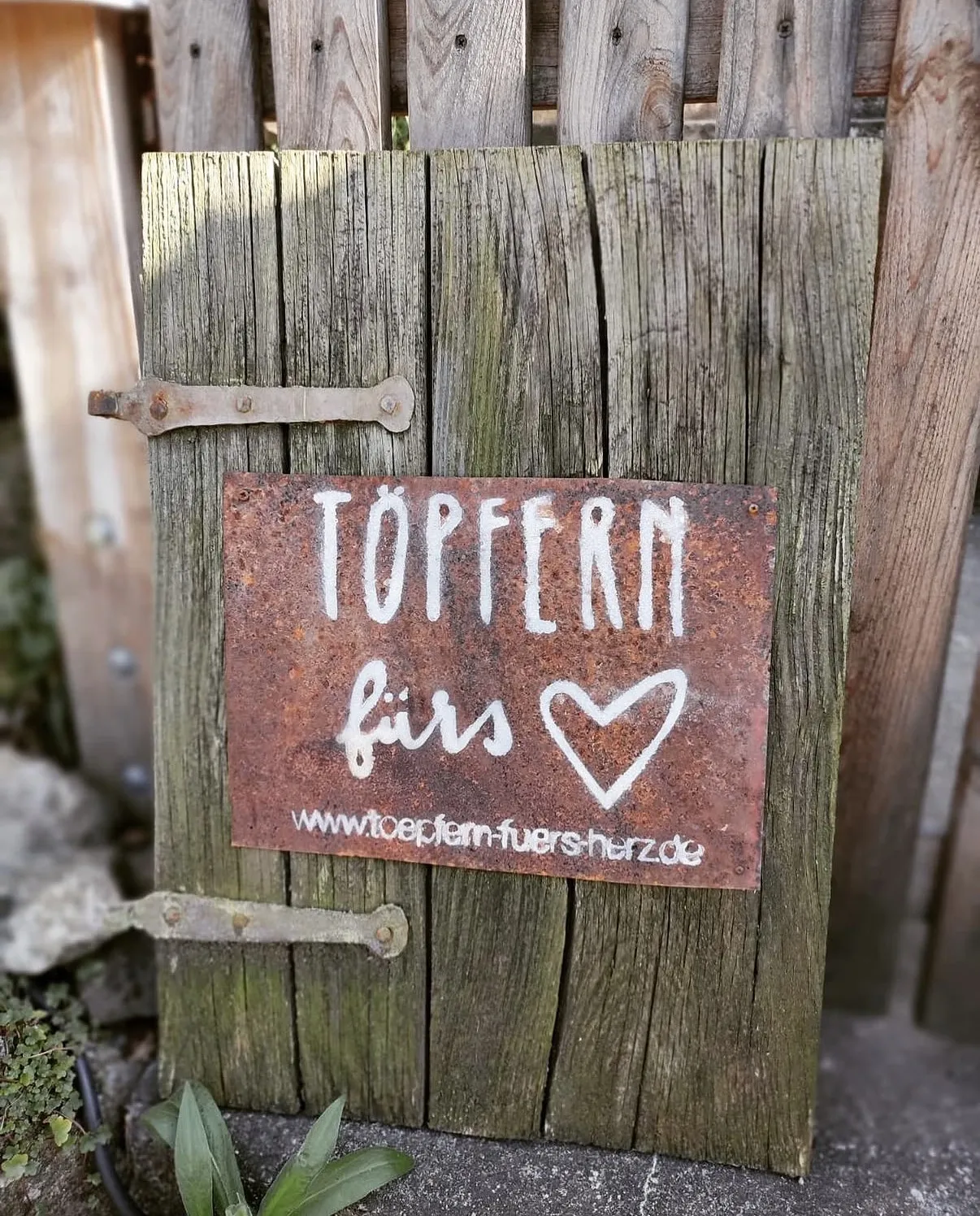 Das Türschild von Töpfern fürs Herz auf einer alten Holztür im Atelier
